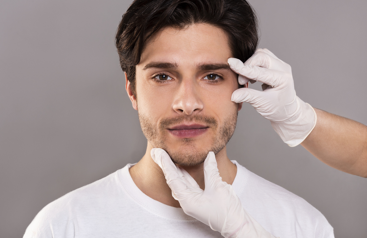 The image shows a beautician massaging the face of young handsome man to visualize what the types of non-surgical forehead lifts are.